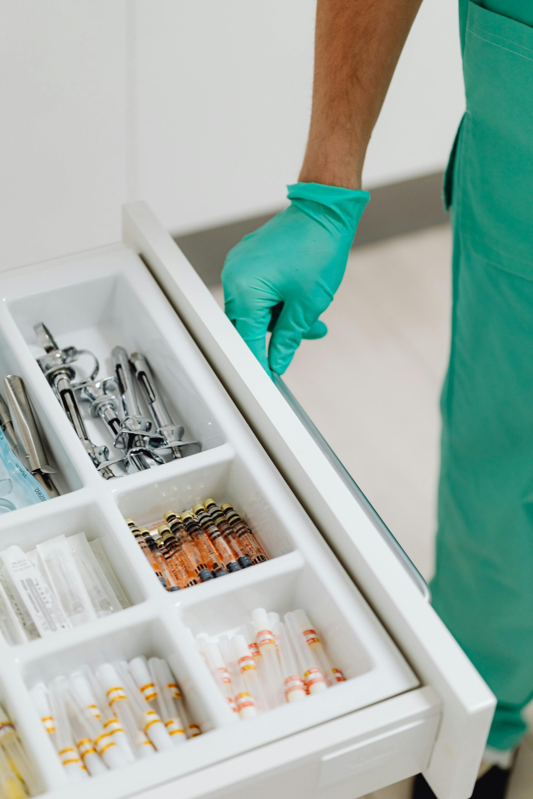 A medical professional opening a drawer filled with syringes and medical tools.